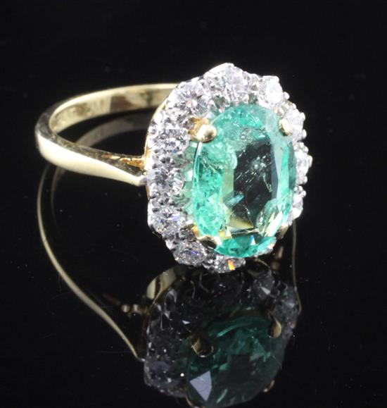 An 18ct gold and platinum, emerald and diamond cluster ring, size O.